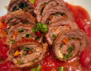 Steak rolls filled with spinach and gouda cheese in a tomato sauce