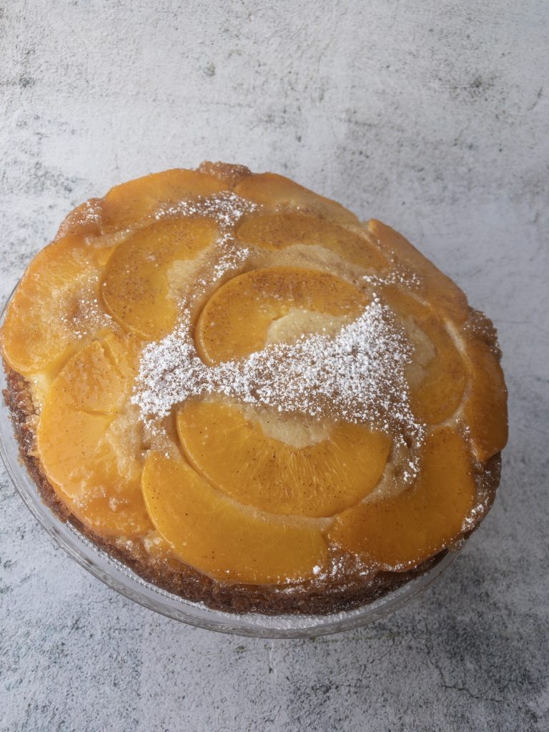Upside down peach cake decorated iwth icing sugar