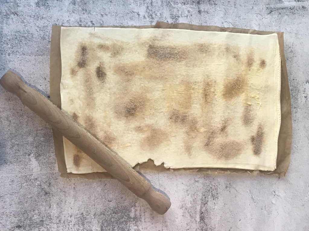 Image of puff pastry sprinkled with cinnamon and sugar with rolling pin