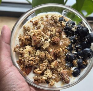 bowl of yogurt topped with granola, fruits and peanut butter